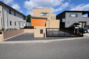 塗り壁門柱と存在感のあるオーバードアで引き締めた、全体的に落ち着いた配色のシンプルモダン外構。