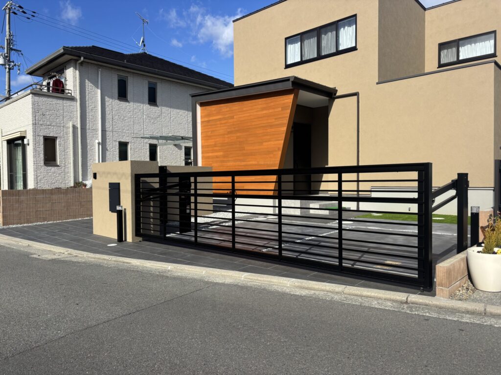 塗り壁門柱と存在感のあるオーバードアで引き締めた、全体的に落ち着いた配色のシンプルモダン外構。