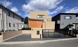 塗り壁門柱と存在感のあるオーバードアで引き締めた、全体的に落ち着いた配色のシンプルモダン外構。