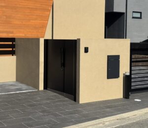 塗り壁門柱と存在感のあるオーバードアで引き締めた、全体的に落ち着いた配色のシンプルモダン外構。
